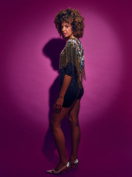 Woman wearing a sequin jacket against a purple background